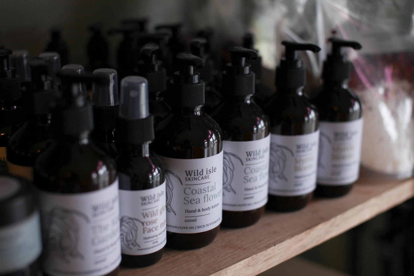 Row of black bottles with white labels on a wooden shelf, featuring 'Wild Isle' branding.