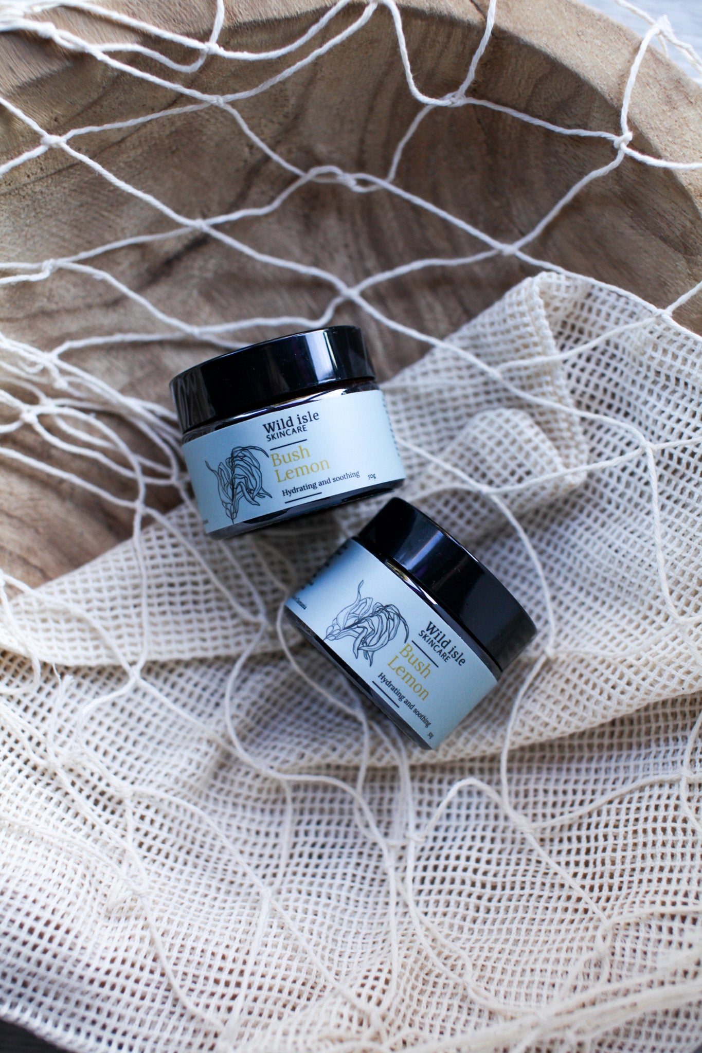 Two jars of Wild bush lemon cream on a textured fabric background